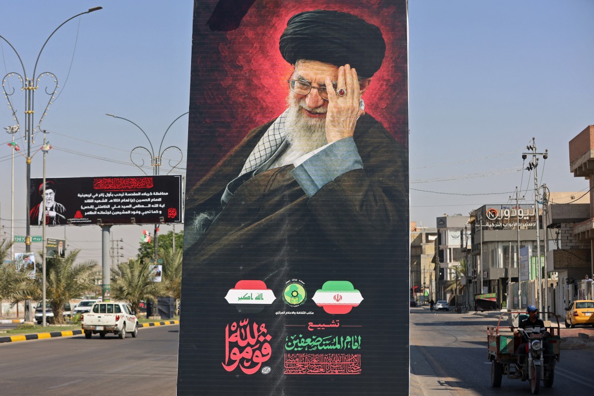 دانانی پۆستەری وێنەی ئایەتوڵا عەلی خامنەیی لە شەقامەکانی شاری نەجەف، وەک ئامادەکارییەک بۆ ڕێوڕەسمی ماڵئاوایی لە تەرمەکەی. فۆتۆ: AFP