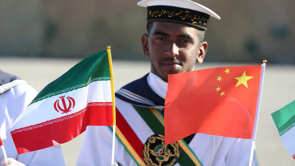 دەریاوانێکی ئێرانی لە کاتی مەشقی دەریایی هاوبەشی ئێران و ڕووسیا و چین، ئاڵای ئێران و چین بەرز دەکاتەوە. فۆتۆ: AFP 