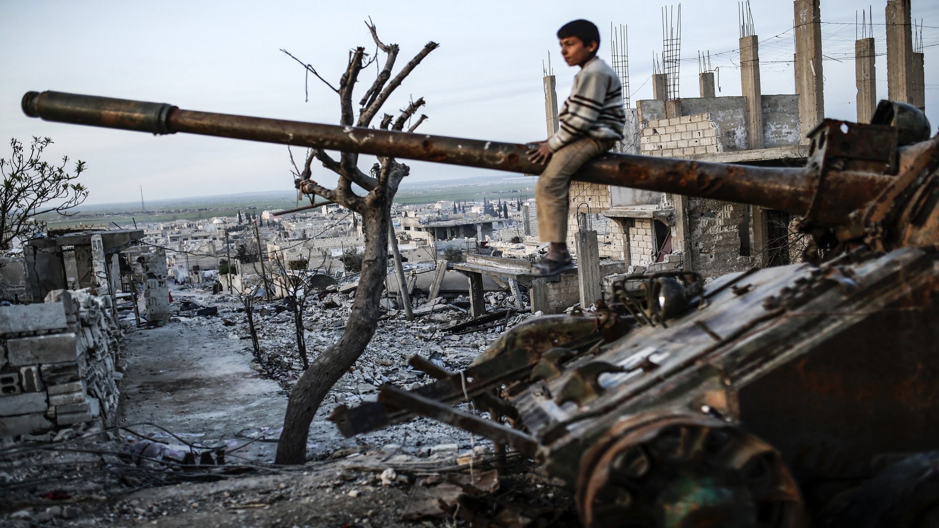 A Syrian Kurdish boy sits on a destroyed tank in the Syrian town of Kobane, also known as Ain al-Arab, on March 27, 2015. Islamic State (IS) fighters were driven out of Kobane on January 26 by Kurdish and allied forces. AFP PHOTO/YASIN AKGUL        (Photo credit should read YASIN AKGUL/AFP/Getty Images)
